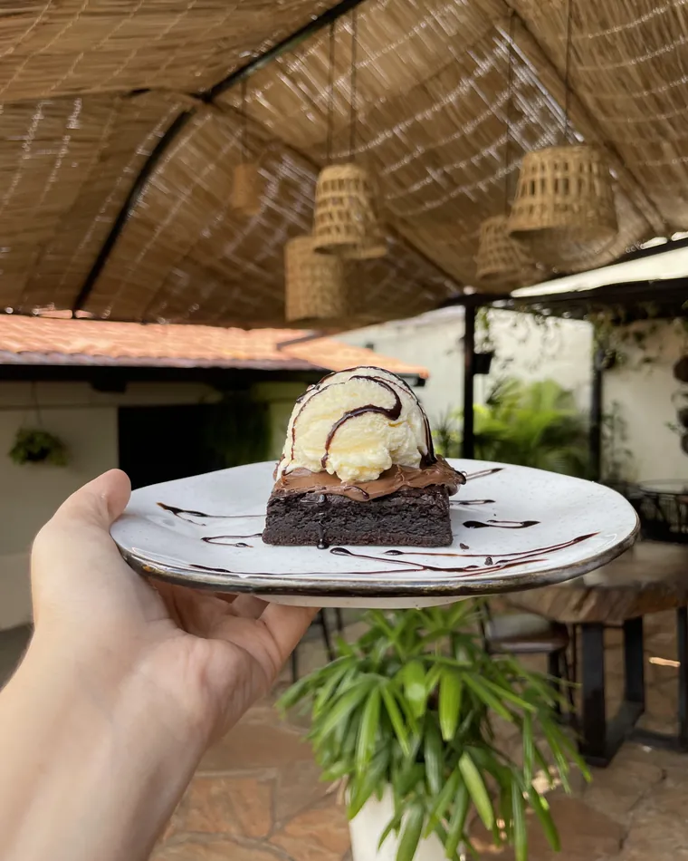 Brownie com bola de sorvete e calda servido no quintal